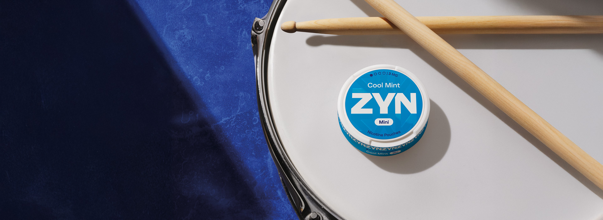 Blue ZYN Cool Mint can above a drum and near some drumsticks